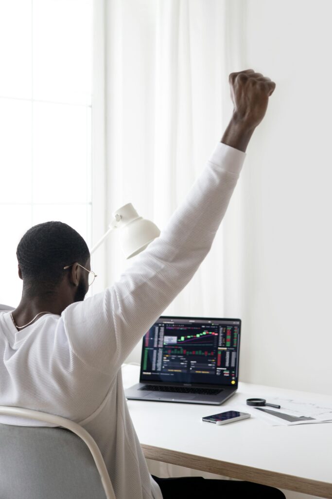 pexels-photo-6801633-6801633 A man celebrates a successful stock market trade while sitting at his desk.